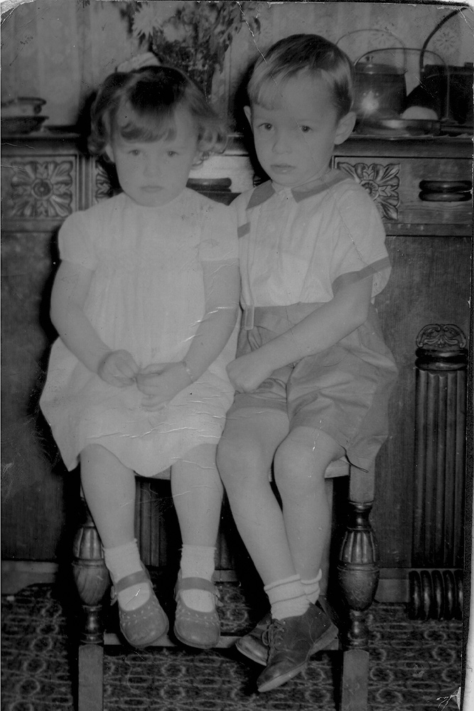 Old black‑and‑white portrait of two young children sitting together, ideal for showcasing professional photo restoration services.