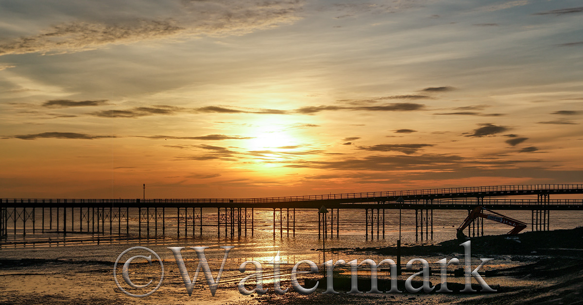 Sunset photo with a pier and a visible watermark across the image, demonstrating how to create a watermark in Photoshop.
