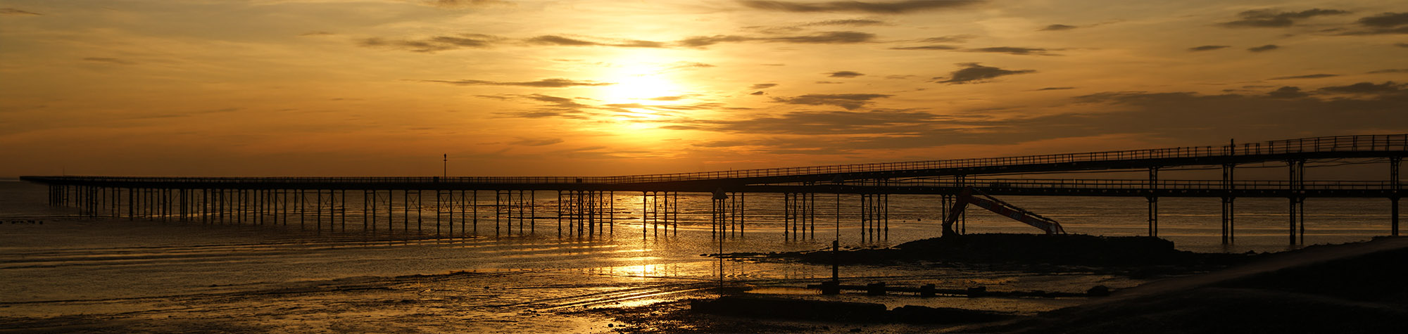 a panoramic image displaying a sunset photo with a pier, ideal for demonstrating how to create a watermark in Photoshop.